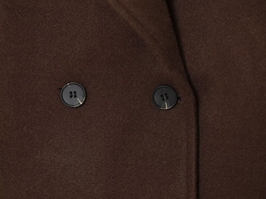 Detail shot of dark brown wool coat showing textured fabric and marble-patterned buttons