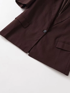 Detail of dark brown short sleeve blazer with button, notch lapel and flap pockets
