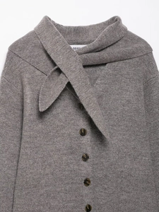 Detailed texture of dark grey knit cardigan with scarf tie and tortoiseshell buttons