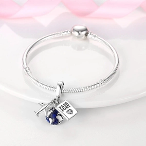 Detail of 925 sterling silver snake chain bracelet with airplane, globe, and passport charms