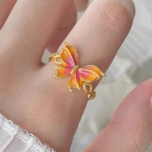 Detail of a butterfly ring with pink and orange enamel and adjustable gold band