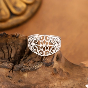 Vintage hollow patterned silver stainless steel ring displayed on a natural wood base