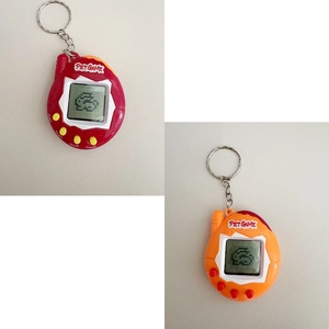 Close-up of retro virtual pet game keychains in red and orange colors with LCD screen
