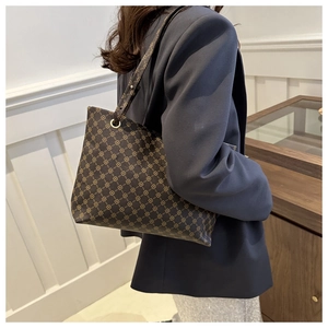 Detail view of large brown vintage monogram shoulder bag with geometric print and thin straps