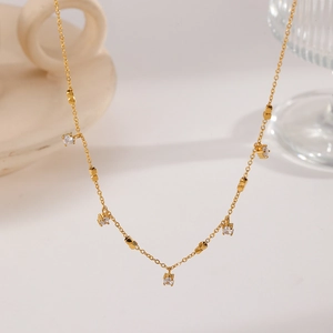 Macro shot of gold-plated titanium necklace featuring five prong-set clear zircon charms