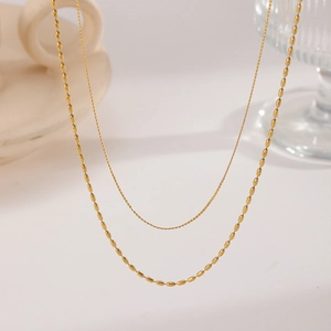 Close-up of double-layered gold titanium necklace with fine chain and beaded details