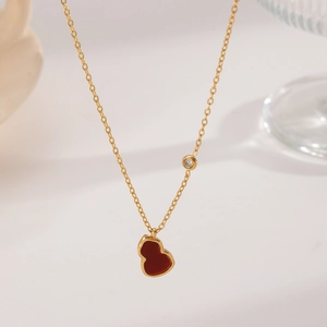 Macro shot of gold chain necklace featuring red gourd pendant and small zircon stone
