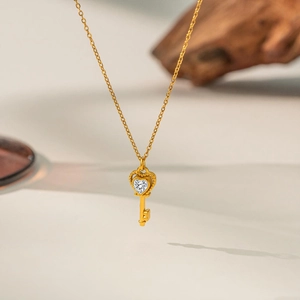 Detail of heart-shaped key pendant with sparkling crystal on a gold titanium steel chain
