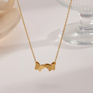 Detailed close-up of golden double butterfly pendant with elegant matte finish on O-chain