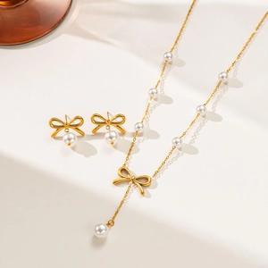 Detailed view of gold bow-knot jewelry set with pearls and Y-shaped pendant necklace
