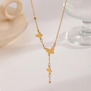 Detail shot of golden butterfly tassel necklace with layered metallic charms and beads