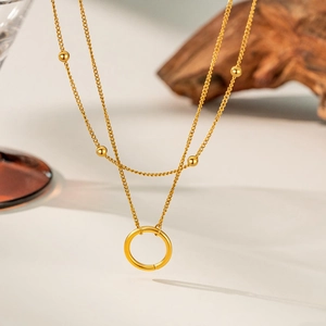 Detailed view of a gold-layered necklace featuring small beads and a circular ring pendant