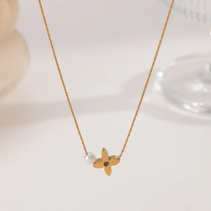 Macro shot of gold-plated titanium necklace with pearl and four-leaf floral pendant