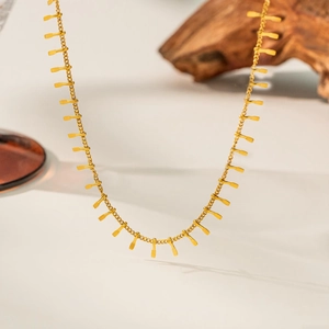 Close-up of a gold titanium necklace featuring minimalist vertical paddle pendant accents