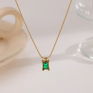 Close-up of rectangular emerald green gemstone pendant on a gold titanium steel chain