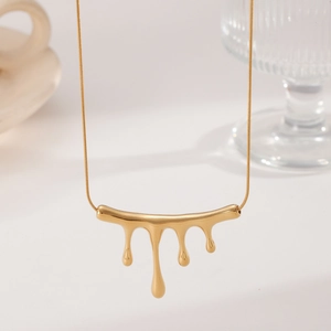 Detail shot of the polished golden lava pendant and sleek snake chain on a minimalist surface