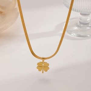 Detailed view of a gold clover pendant on a sleek snake chain over white background