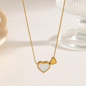 Macro shot of double heart pendant necklace with mother of pearl inlay and gold chain