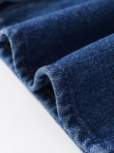 Close-up of premium dark blue denim fabric showing detailed twill weave and cotton texture