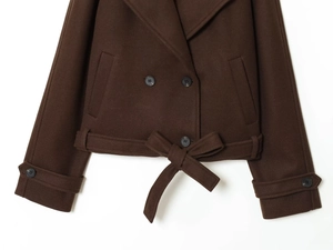 Detail of dark brown wool jacket featuring double-breasted buttons and waist tie-up bow