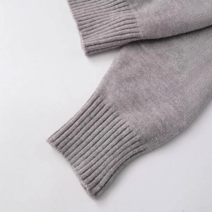 Close-up of soft grey knit sweater with detailed ribbed cuff texture on white background