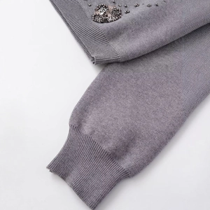 Grey beaded knit cardigan featuring ribbed cuffs and handmade sequin details on a white backdrop