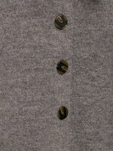 Close-up of grey wool blend knit fabric with three dark brown marble pattern buttons