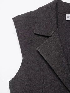 Detail view of V-neck knitted vest neck area with texture and brand label closeup