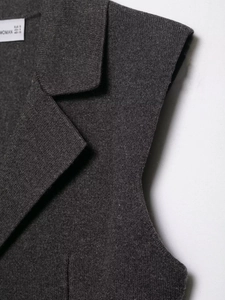 Detailed view of the dark grey knit vest collar showing the woven label and fine stitching