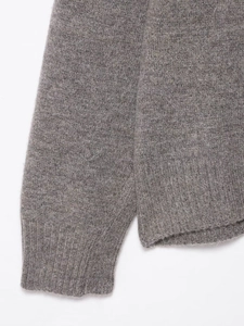 Detailed macro view of the grey knit sweater showing ribbed cuffs and soft wool texture