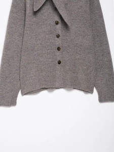 Detailed close-up of dark grey knitted cardigan with sharp collar and buttons