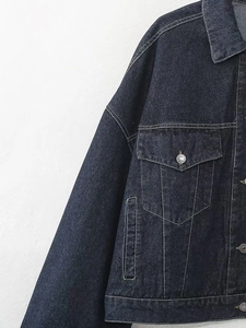 Détail de la veste en jean bleu marine avec coutures contrastées et boutons métalliques