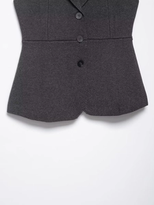 Detail view of charcoal grey knit vest featuring three black buttons and premium texture