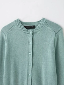 Macro view of mint green knit cardigan collar with buttons and brand label