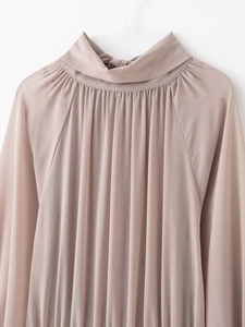 Detail of elegant dusty pink high-neck top with intricate pleat design and soft texture