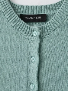 Close-up of mint green knit cardigan featuring round neck and ribbed texture details