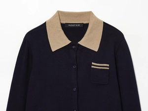 Detail of navy knit cardigan featuring khaki contrast collar and striped chest pocket