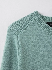 Close-up of mint green knit cardigan neckline showing ribbed texture and stitching detail