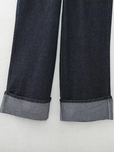 Détail de l'ourlet large à revers sur un jean denim bleu foncé avec des coutures soignées