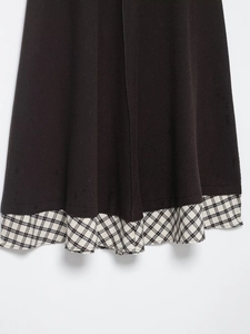 Detail view of dark twill fabric stitching with beige plaid pattern on a knit dress