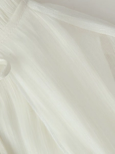 Detail shot of white ruffled fabric with delicate pleated texture and side tie string