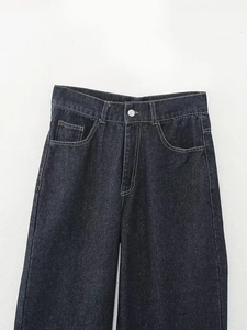 Détail du jean taille haute en denim foncé avec bouton métallique et poches classiques