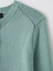 Close-up of mint green knit cardigan featuring raglan sleeves and delicate stitching