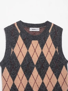 Primer plano del chaleco de punto vintage con rombos gris y naranja y etiqueta marca