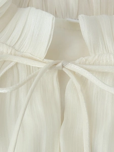 Detailed view of the pleated cream dress neckline with delicate drawstring ties
