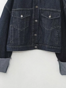 Détail de la veste en jean bleu foncé avec boutons métalliques et poches à rabat
