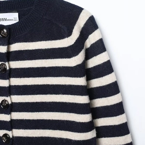 Detail of round neckline and tortoiseshell buttons on a striped knit cardigan