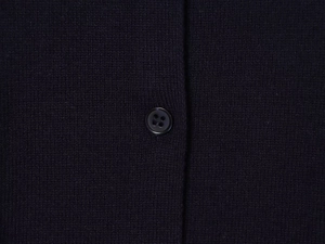Close-up of a black four-hole button on fine knit polo sweater fabric with clean texture