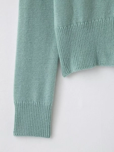 Detail of mint green knit cardigan showing ribbed cuffs and fine needlework texture