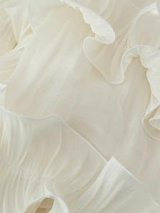 Detailed macro view of white ruffled chiffon fabric with elegant pleated texture and soft edges